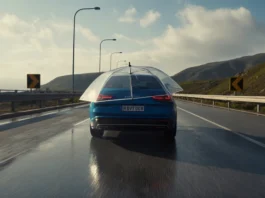 Automobilis važiuoja tarptautiniu keliu po skaidriu, apsauginiu skėčiu.