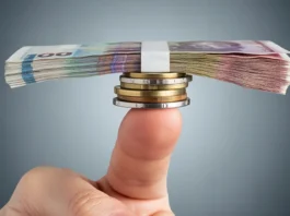 Banknotų ir monetų krūva vienu piršto galiuku subalansavo.